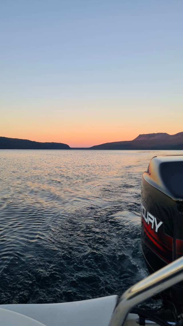 boat water lake sunset horizon mountains sky engine waves reflection orange blue black white landscape boating nature outdoor travel serene calm twilight dusk