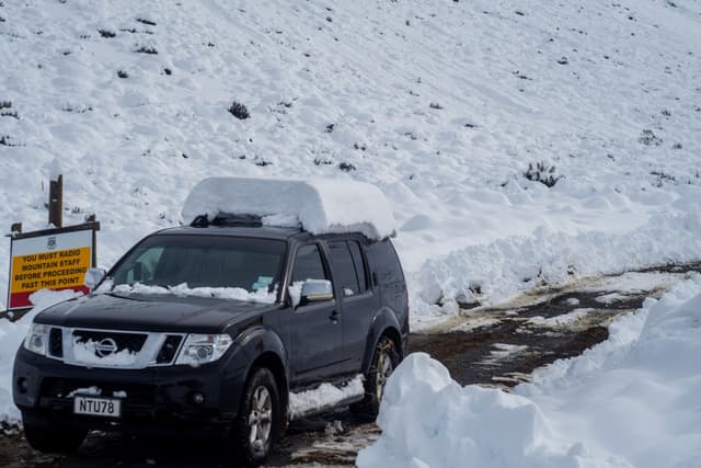 snow car vehicle road winter landscape mountain signboard snow-covered roof black white cold travel outdoor nature ice transportation path journey scenery frozen weather driving adventure trip exploration remote rugged terrain environment season automobile journeying expedition snowy primary-color-white