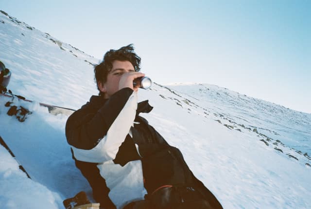 Person Snow Mountain Drinking Bottle Jacket Winter Blue Sky Cold Outdoor Relaxing Slope White Black Beverage Landscape Leisure Adventure Nature Scenery Chill Refreshment Recreation Calm Peaceful Quiet Solitude Tranquility