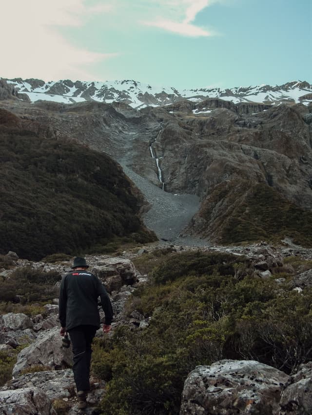 mountain snow rocks hiker walking landscape nature outdoors sky clouds greenery trail path adventure exploration wilderness scenery terrain travel trekking hiking backpacking remote rugged primary blue
