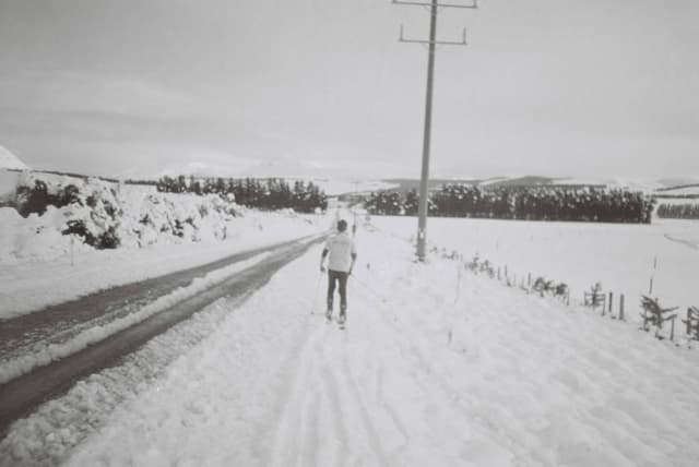 snow road person trees power line winter landscape black white field sky fence rural cold pathway outdoors monochrome overcast walking nature scenery countryside travel solitude peaceful serene quiet distant horizon tracks frozen empty calm remote journey exploration adventure tranquility minimalist simple vast open space primary color: white