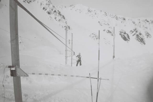 snow mountain ski lift poles cables skier winter white black-and-white landscape outdoor cold slope equipment skiing alpine sport frozen icy remote high-altitude adventure travel recreation nature rugged serene peaceful quiet isolated monochrome vintage retro