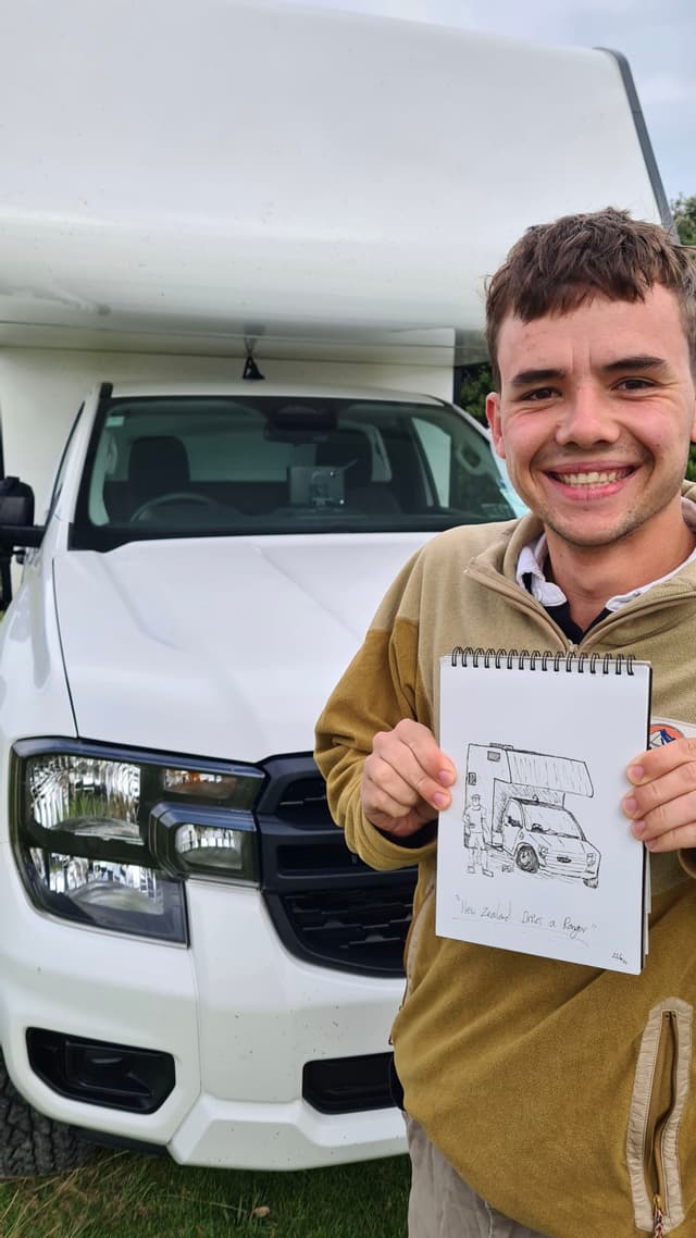 White vehicle van person drawing sketch paper grass outdoors smile headlights front view brown hair beige jacket sky daytime