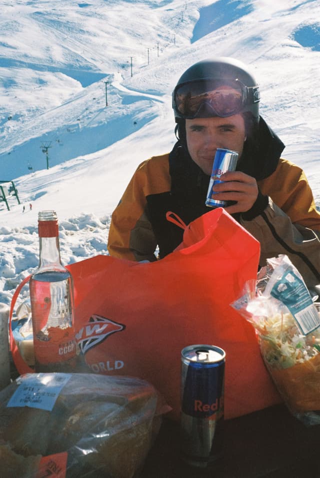 snow helmet goggles jacket person drink can bottle bag bread chips table outdoor winter red white blue sky mountain ski