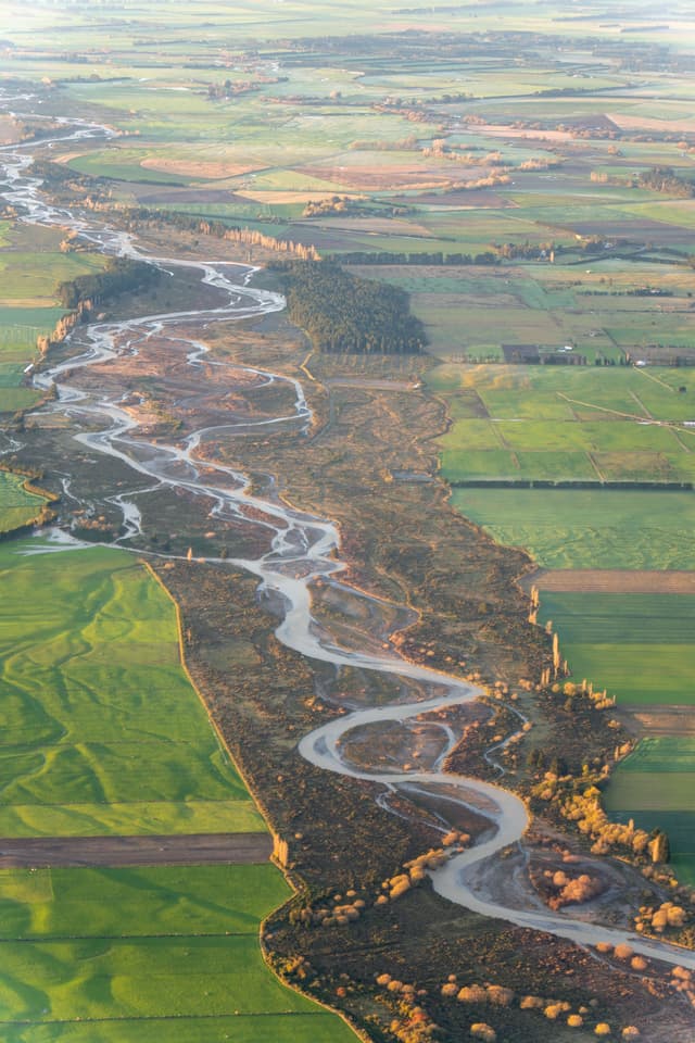 River Landscape Aerial View Fields Green Brown Water Trees Vegetation Meandering Stream Agriculture Farmland Nature Scenery Countryside Terrain Earth Pattern Flow Natural Environment Outdoors Rural Scene Winding Curves Horizon Sky Primary Color Green