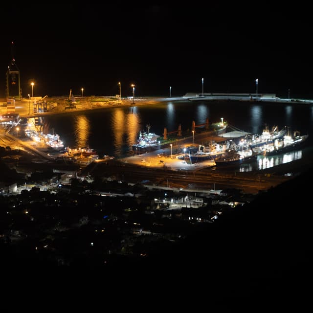night harbor lights water reflection ships boats docks pier buildings cranes dark orange black