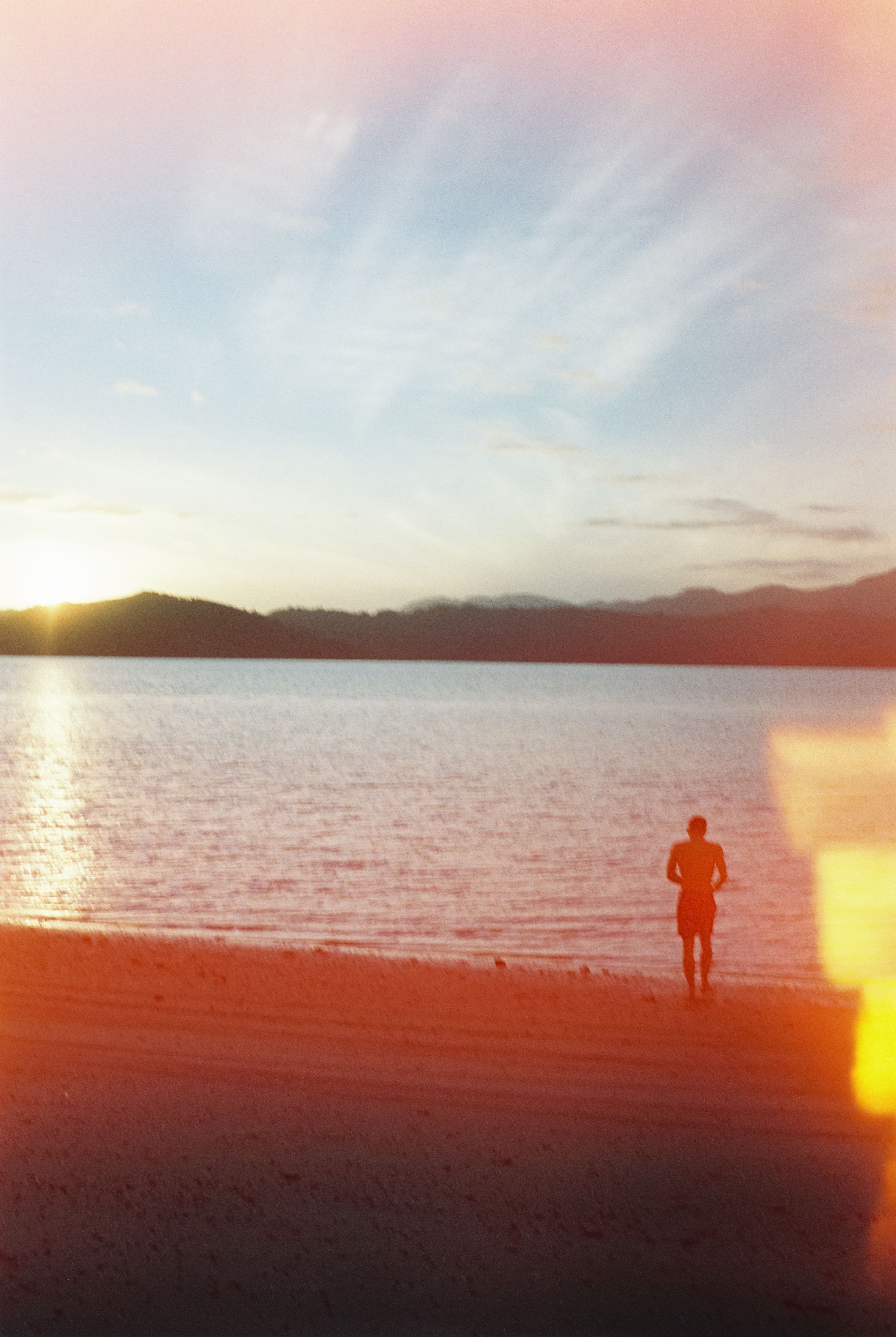 Beach Water Sunset Silhouette Person Sky Clouds Mountains Horizon Sand Reflection Light Blue Orange Yellow