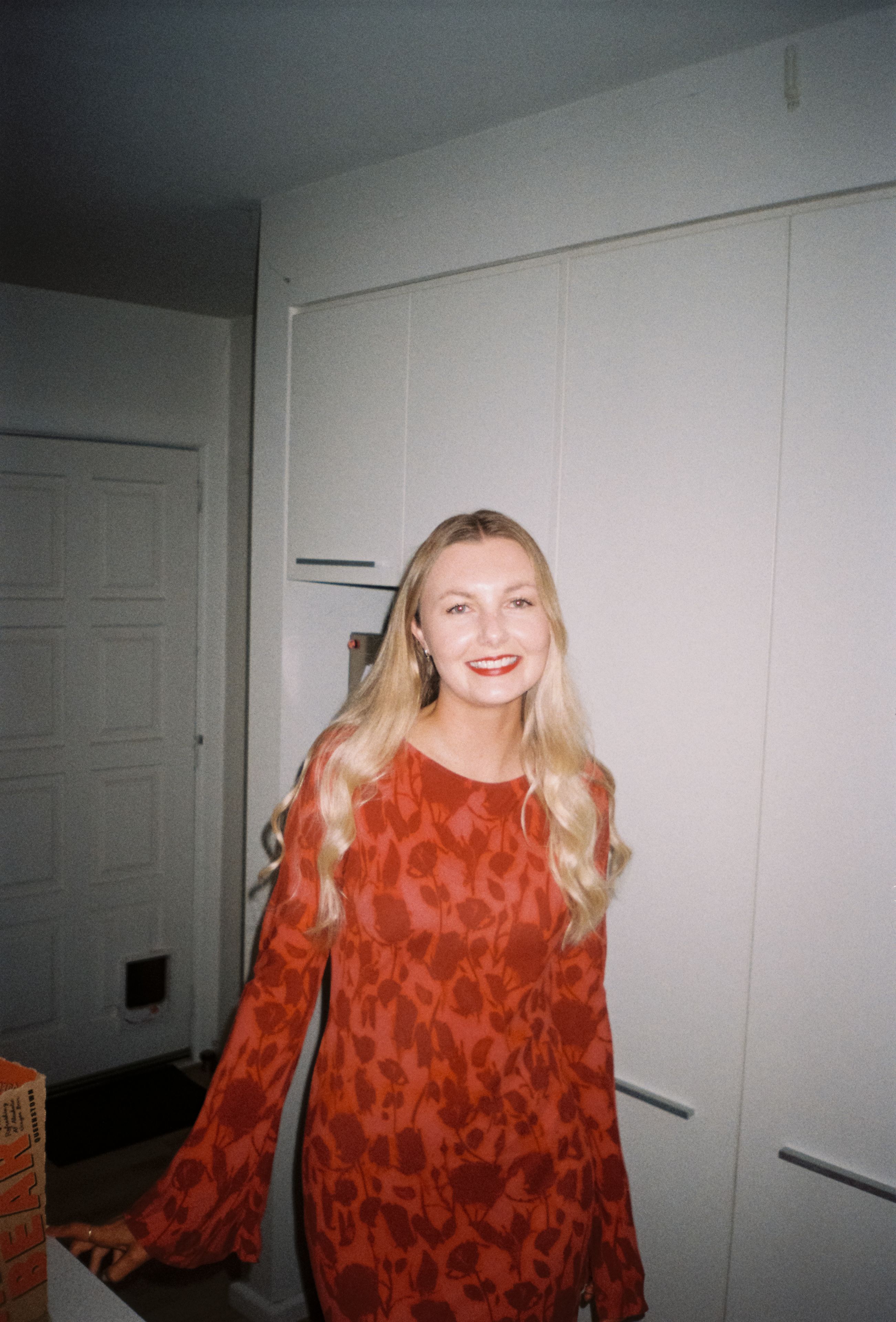 woman dress red pattern smile blonde hair kitchen cabinets door white wall ceiling light fixture