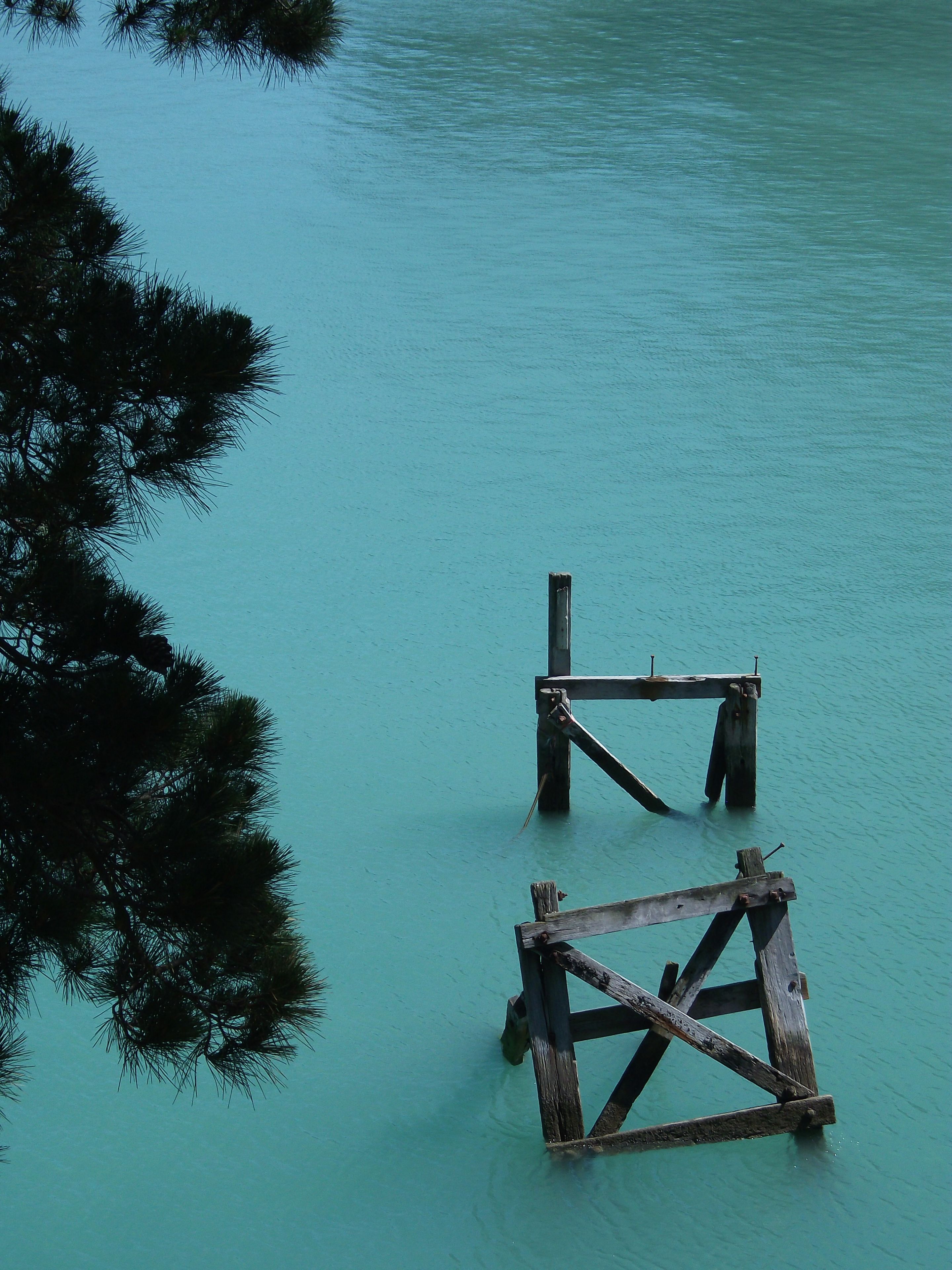 Water Turquoise Tree Branches Wooden Structure Pier Calm Nature Outdoors Reflection Tranquil Scenic Blue Green Sky Peaceful Serene Landscape Abandoned Weathered Old Ruins Stillness Quiet Natural Beauty Environment Tranquility