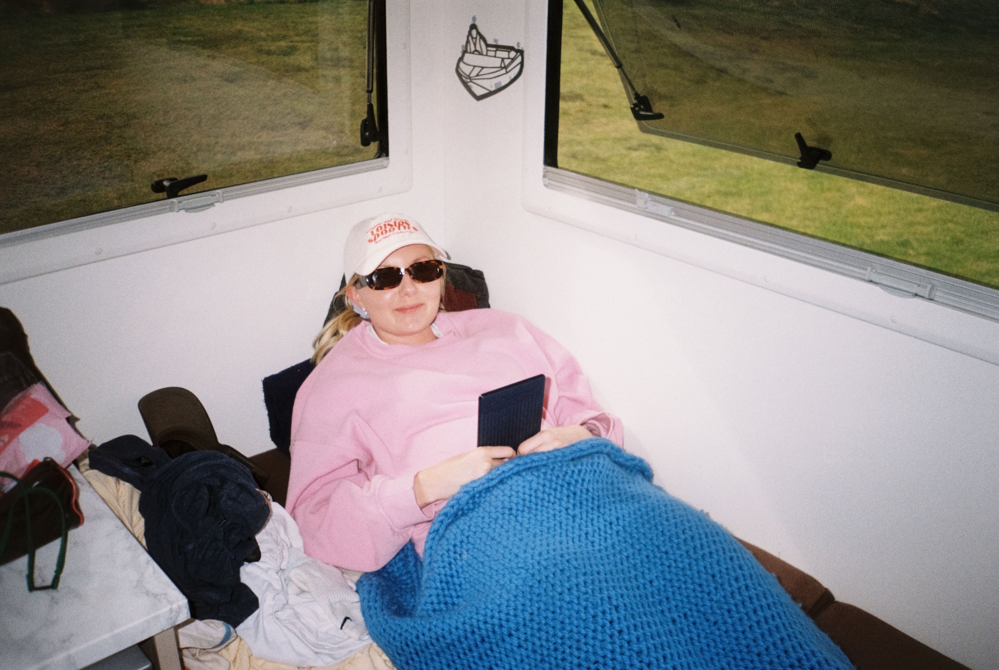 person sunglasses hat pink blue blanket book window chair bag white black brown green