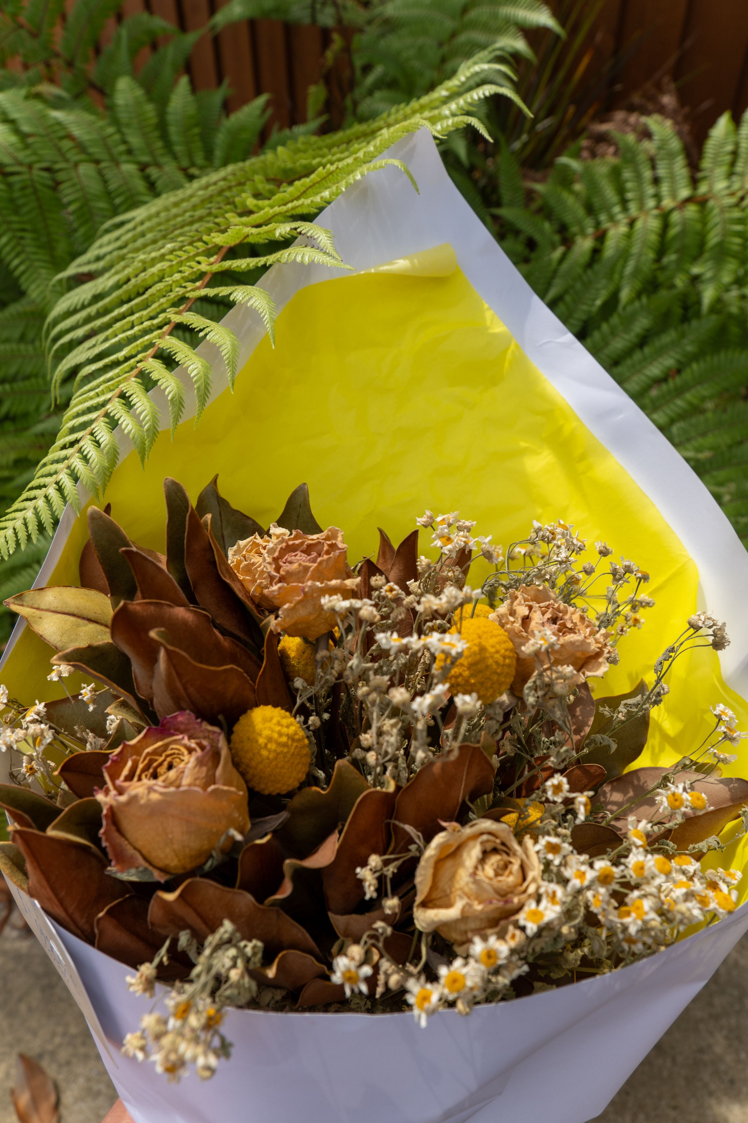 Bouquet Flowers Dried Roses Yellow White Brown Green Fern Leaves Wrapping Paper Arrangement Floral Nature Petals Stems Foliage Decorative Gift Present Natural Rustic Elegant Beautiful Botanical Garden Outdoor Freshness Texture Contrast Aesthetic Composition