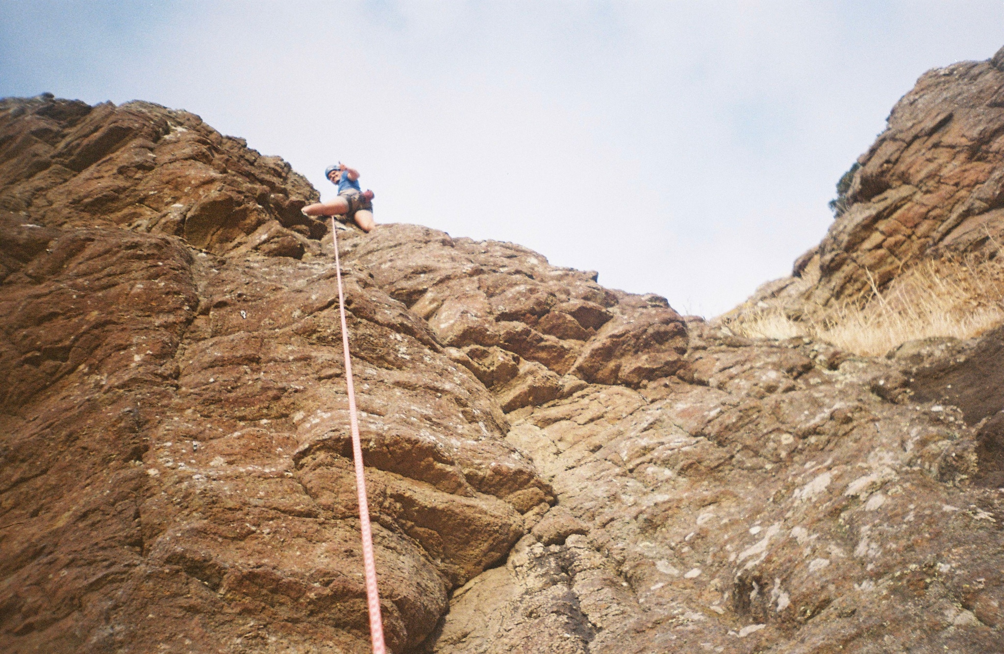 Climbing Rock Climber Rope Mountain Outdoor Adventure Sky Brown Cliff Gear Helmet Harness Blue Rugged Sport Nature Vertical Ascent Challenge Extreme Recreation Landscape Boulder Safety Equipment Steep Terrain Exploration Courage Effort Determination