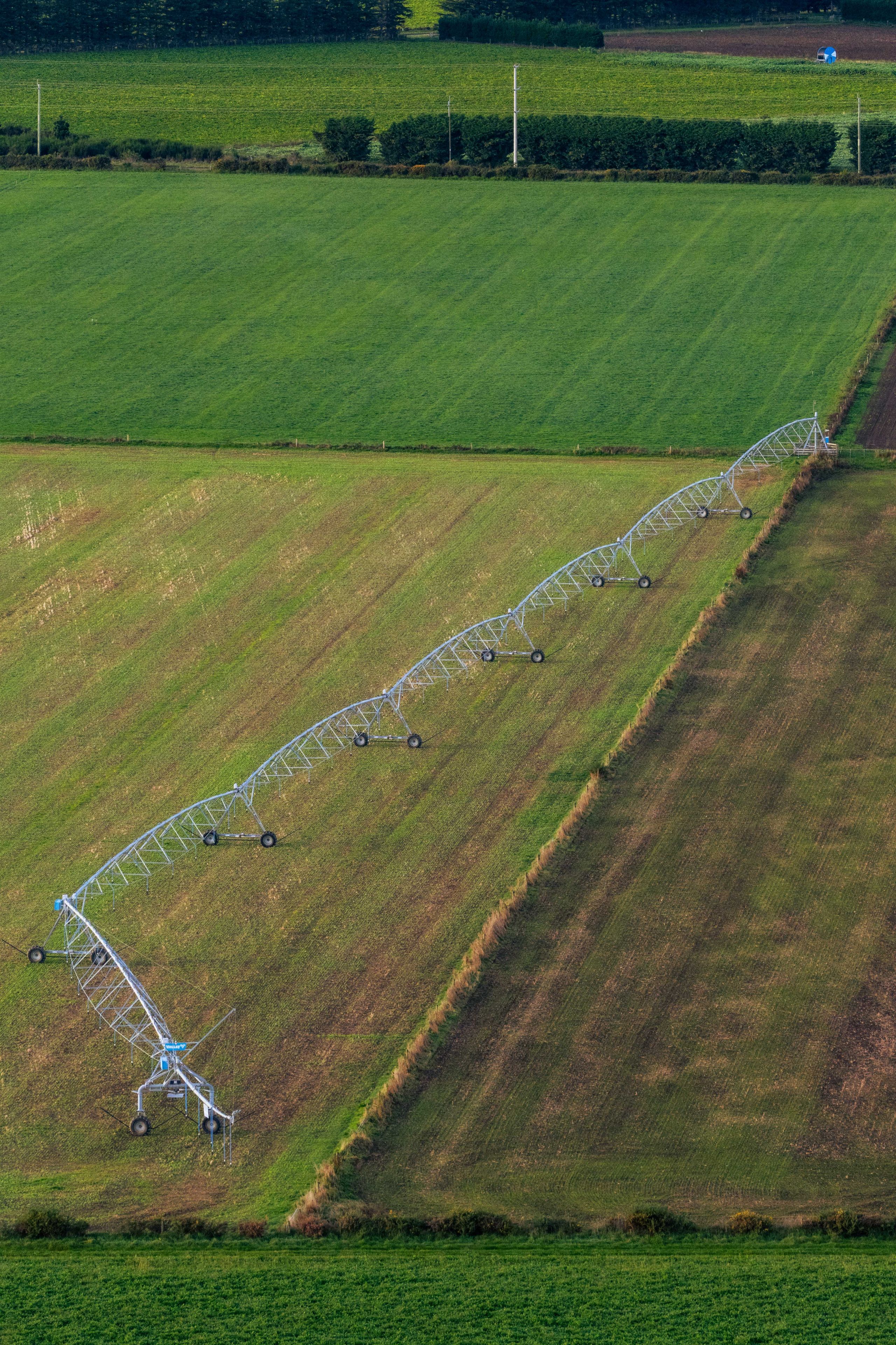Field Farmland Irrigation System Pivot Green Grass Crops Agriculture Farming Machinery Equipment Wheels Structure Aerial View Landscape Rural Countryside Vegetation Lines Patterns Rows Watering System Technology Outdoors Environment Growth Cultivation Harvesting Blue Sky