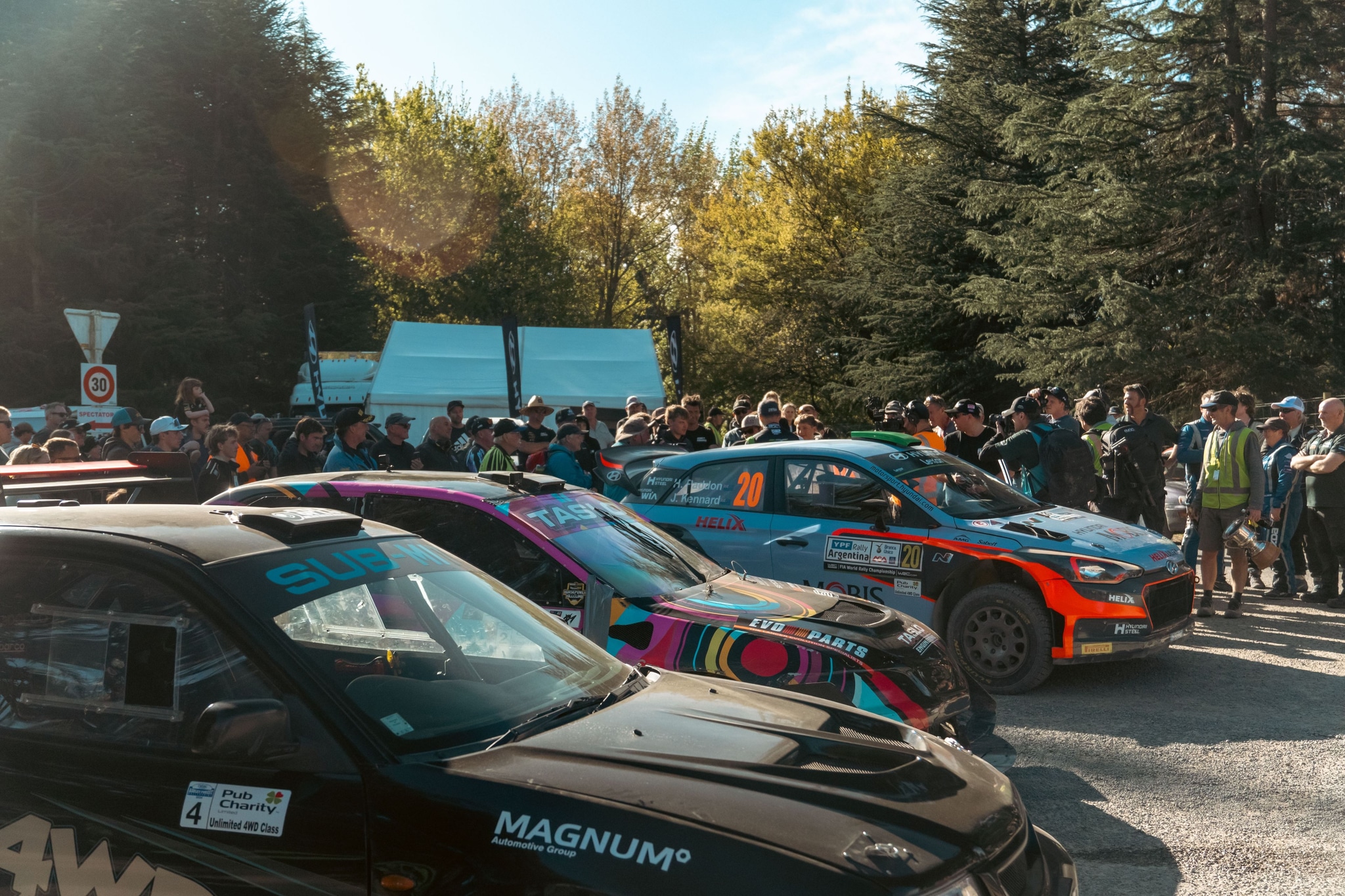 Cars Racing Rally Crowd Trees Forest Road Black Blue Orange Green Sky People Event Outdoors Daytime