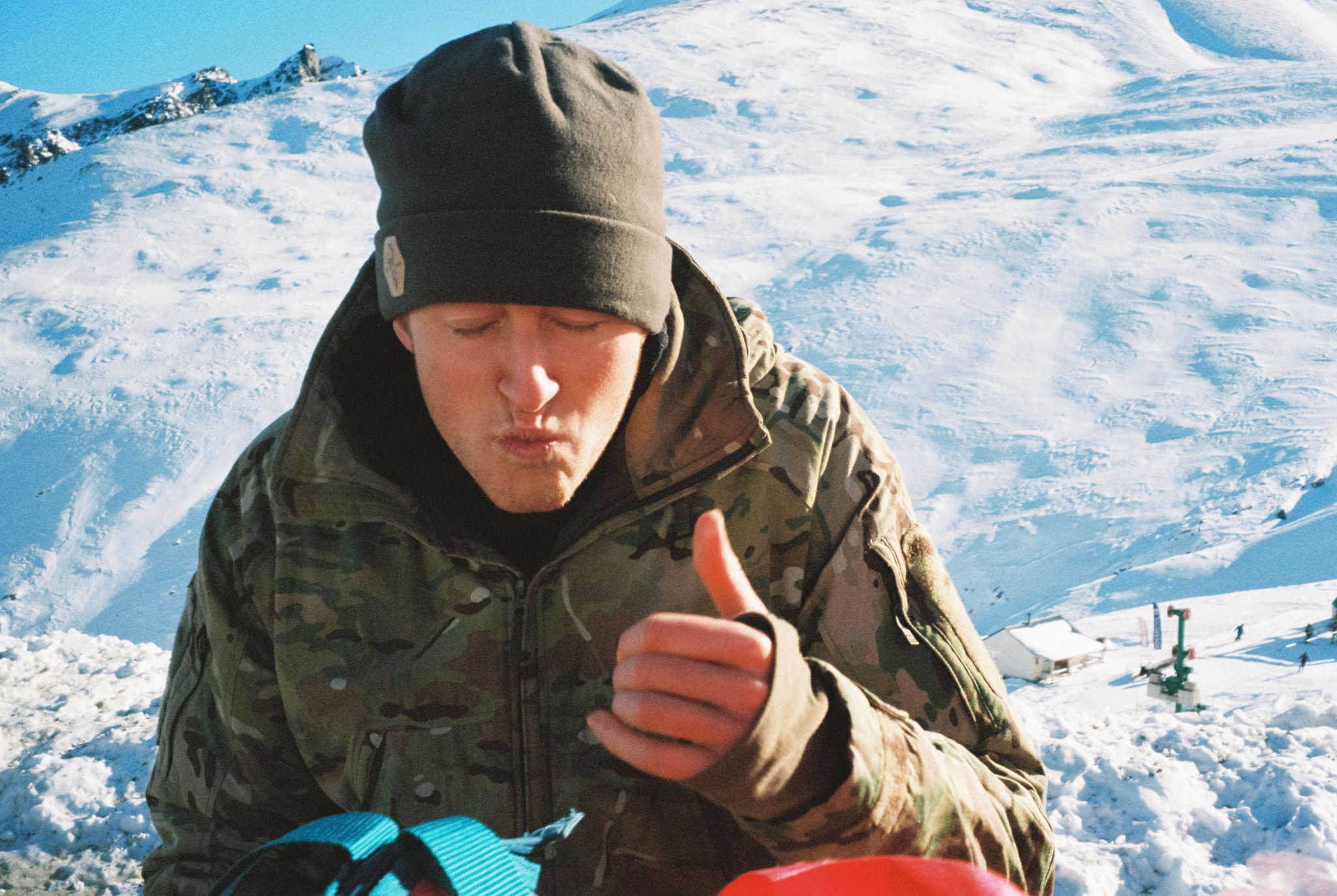 snow mountain winter camouflage jacket beanie hat thumbs up blue sky outdoor cold weather person landscape ice adventure travel nature white skiing snowboarding alpine peak summit frozen scenic sports gear clothing gloves sunlight shadow rugged terrain exploration leisure activity primary color white