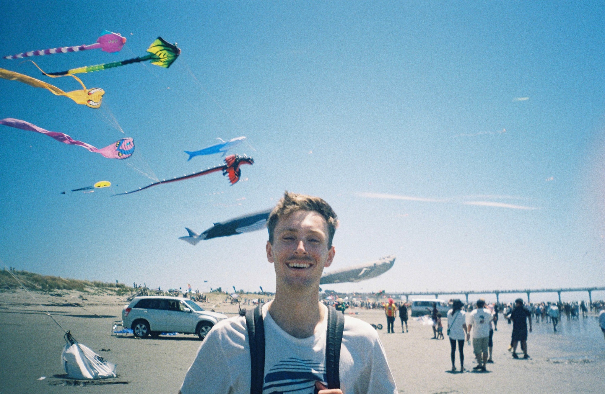 kites beach sky people car sand ocean pier blue colorful flying sunny outdoors festival fun summer day activity gathering shoreline horizon